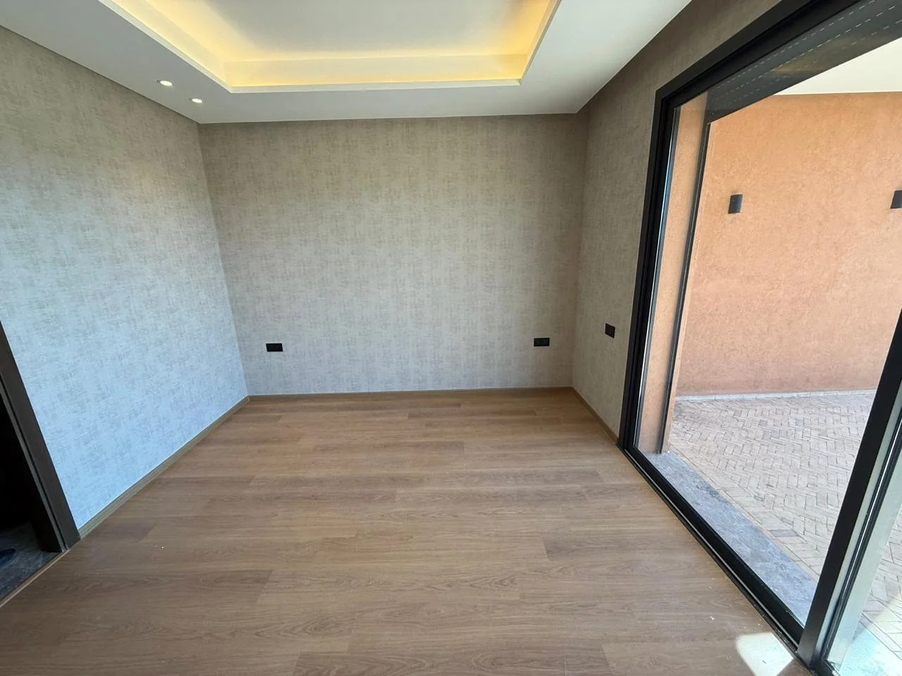 Pièce avec parquet, éclairage intégré et grande baie vitrée dans la villa à Marrakech